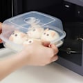 Pikkukuva 3 / 5: Mikroaaltouunin höyrystin muoviastiassa kannen kanssa höyrytettyihin sämpylöihin ja gyozaan (FMY)