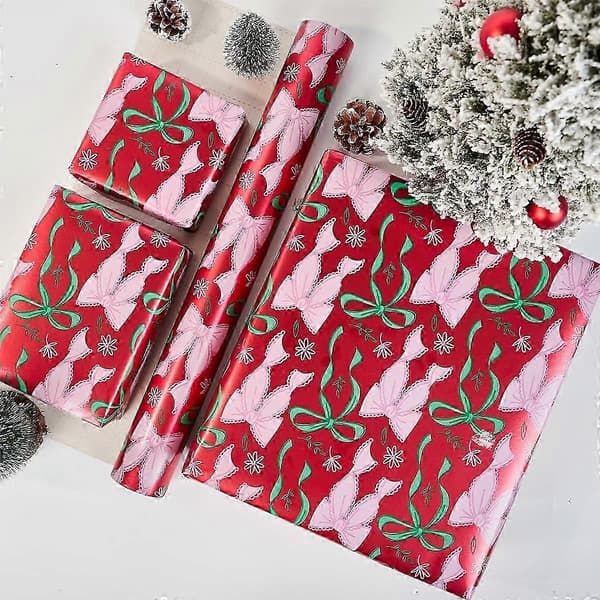 Metalliskt julklappspapper på rulle med rosa snöflingemönster