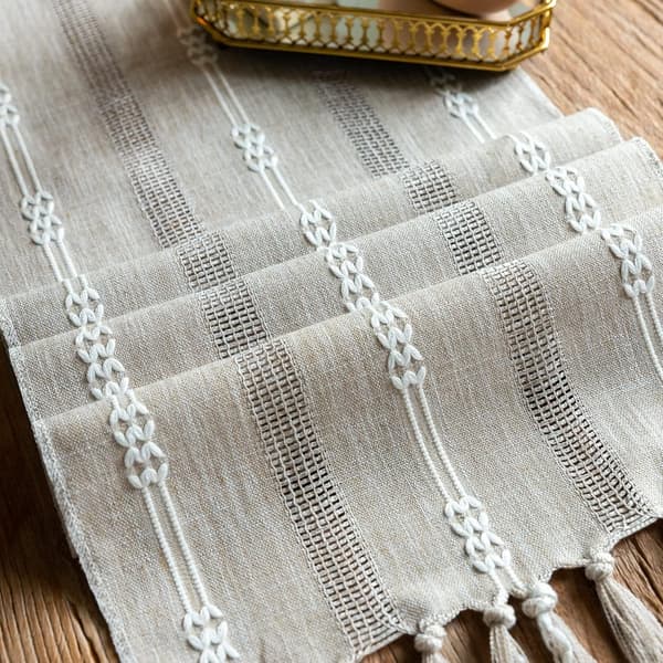 Grå bordløper med håndlagde dusker i lin med uthulet brodert T