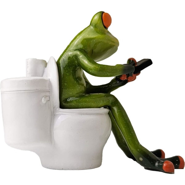 Frosk figur dekorasjon, en frosk som sitter på toalettet og spiller med telefonen sin