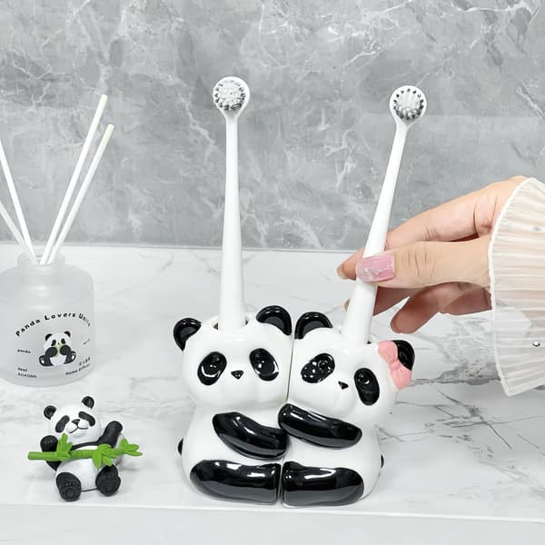 Kaksi keraamista pandaa halaa hammasharjatelinettä White