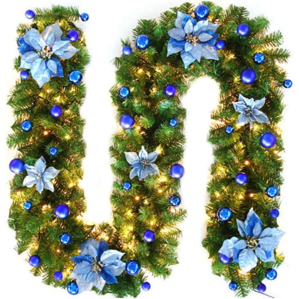 Julekransdekorasjon med lys, kunstige julerottingplanter med blomster og kulepynt, blå julekrans innendørs og