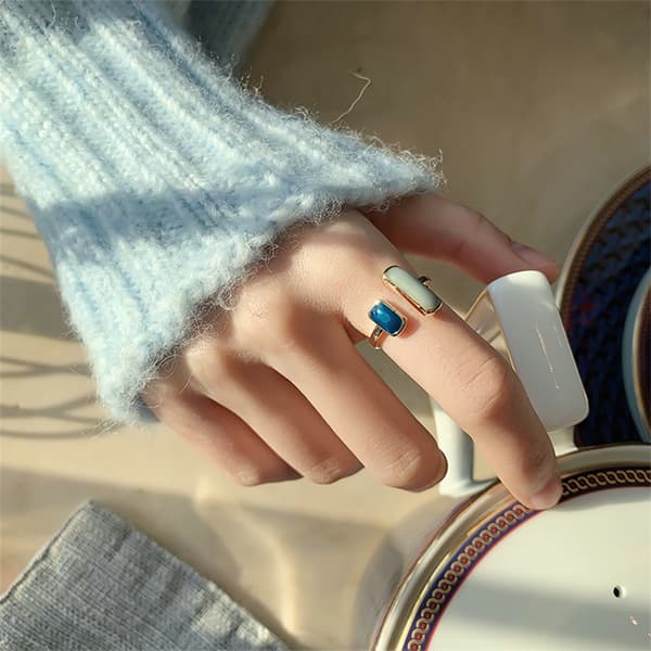 Gullfarget delt åpen ring med lys kremfarget glatt avlang stein og dyp blå glatt firkantet stein, minimalistisk justerbart fingerpynt