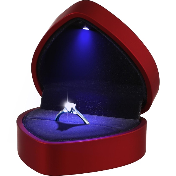 Sydämenmuotoinen sormuslaatikko vaalealla korurasialla vaalealla hääkihlaehdotuksella punaisella)