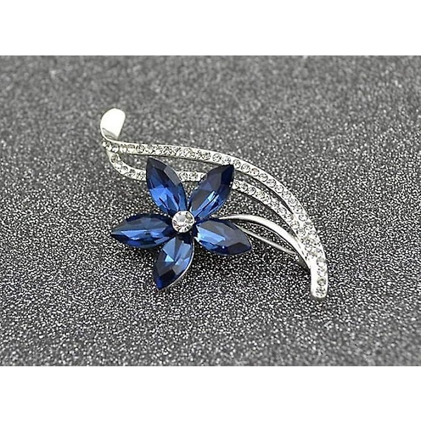 Generisk broche i sølvstål med blomstermotiv, hvide rhinsten og blå østrigske krystaller.