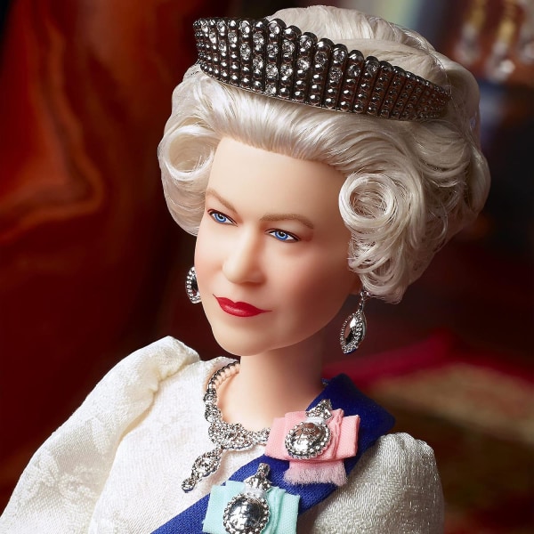 Queen Elizabeth II Platinum Jubilee -nukke norsunluun mekossa, nauhassa, kruunussa ja hansikkaissa nukenpidikkeellä,