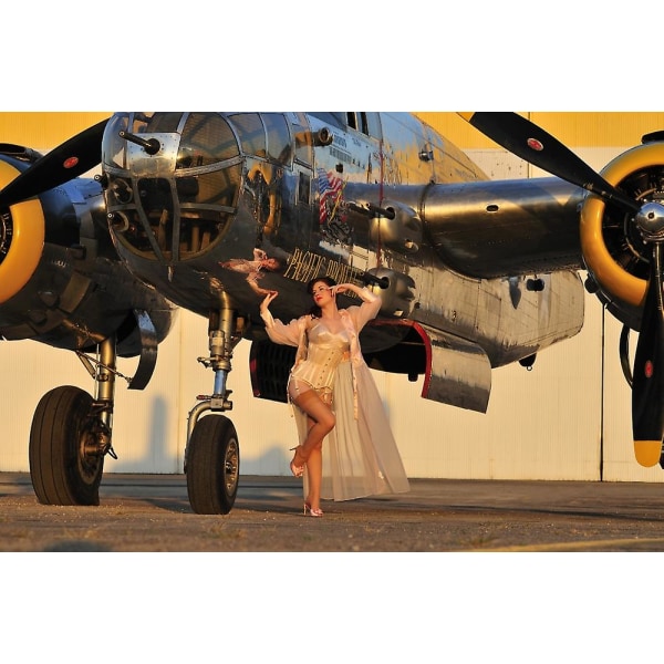 Seksikäs 1940-luvun pin-up tyttö alusvaatteissa poseeraa B-25 pommikoneen kanssa. Juliste