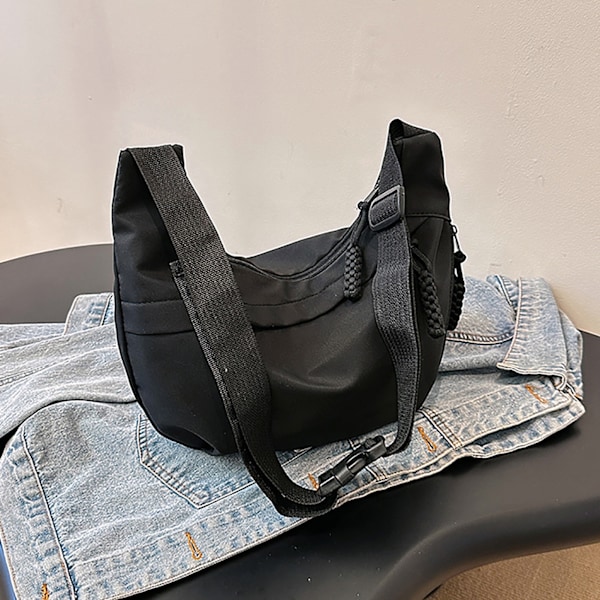 Stor svart axelväska i nylon med justerbar rem och dragkedja för vardagsbruk