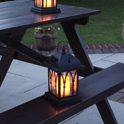 Sort solcelled lanterne med LED-lys, der ligner et ægte stearinlys