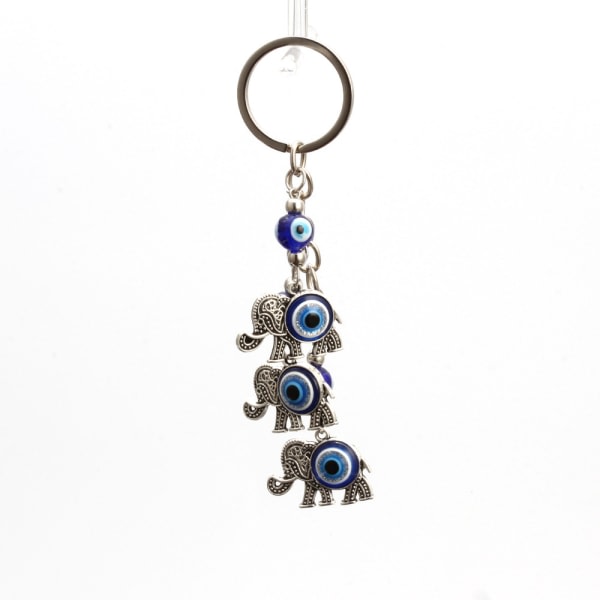 En nyckelring med tre elefanter med blå øyne, hengende vegg med onda ögat, nyckel c IC