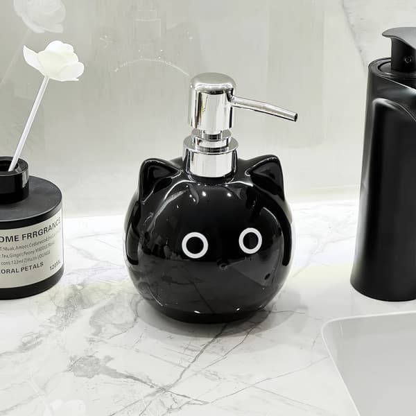 Keraamisessa lotion-pullossa on pyöreäsilmäinen musta kissa -design. black
