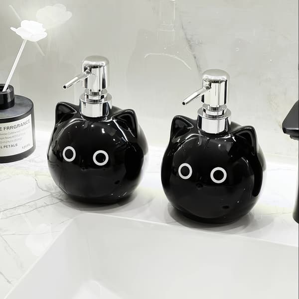 Keraamisessa lotion-pullossa on pyöreäsilmäinen musta kissa -design. black