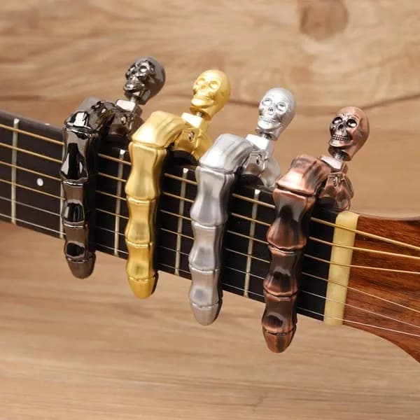 Gitarrkapodaster i dödskalledesign (lämplig för akustiska och elektriska gitarrer) samt ukulelekappodaster, guldfärgad.
