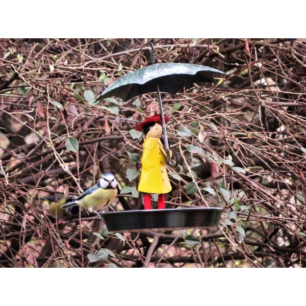 Girl's Metal Bird Mater i hagen med hengende kjede og gammeldags metallparaply for ville fugler